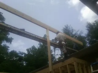 Carpenter setting a ridge beam over a new addition frame — Ice Dam Removal by Roofing Brothers in Mineola